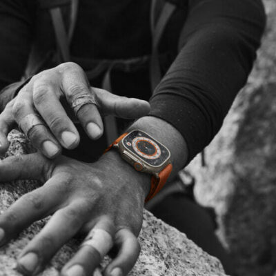 A close-up of two bandaged hands resting on a boulder shows Apple Watch Ultra worn on one of the wrists.