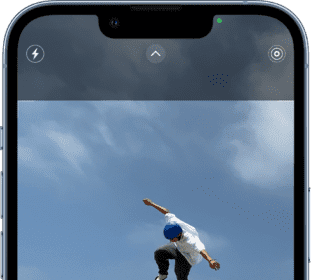 Camera in Photo mode, with other modes to the left and right below the view finder. Buttons for Flash, Camera Controls, and Live Photo appear at the top of the screen. The Photo and Video Viewer button is in the bottom-left corner. The Take Picture button is at the bottom center, and the Camera Chooser Back-Facing button is in the bottom-right corner.  