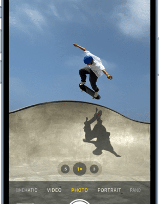 Camera in Photo mode, with other modes to the left and right below the view finder. Buttons for Flash, Camera Controls, and Live Photo appear at the top of the screen. The Photo and Video Viewer button is in the bottom-left corner. The Take Picture button is at the bottom center, and the Camera Chooser Back-Facing button is in the bottom-right corner.  