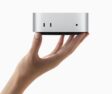 A hand holds the all-new Mac mini.