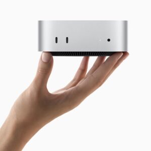 A hand holds the all-new Mac mini.